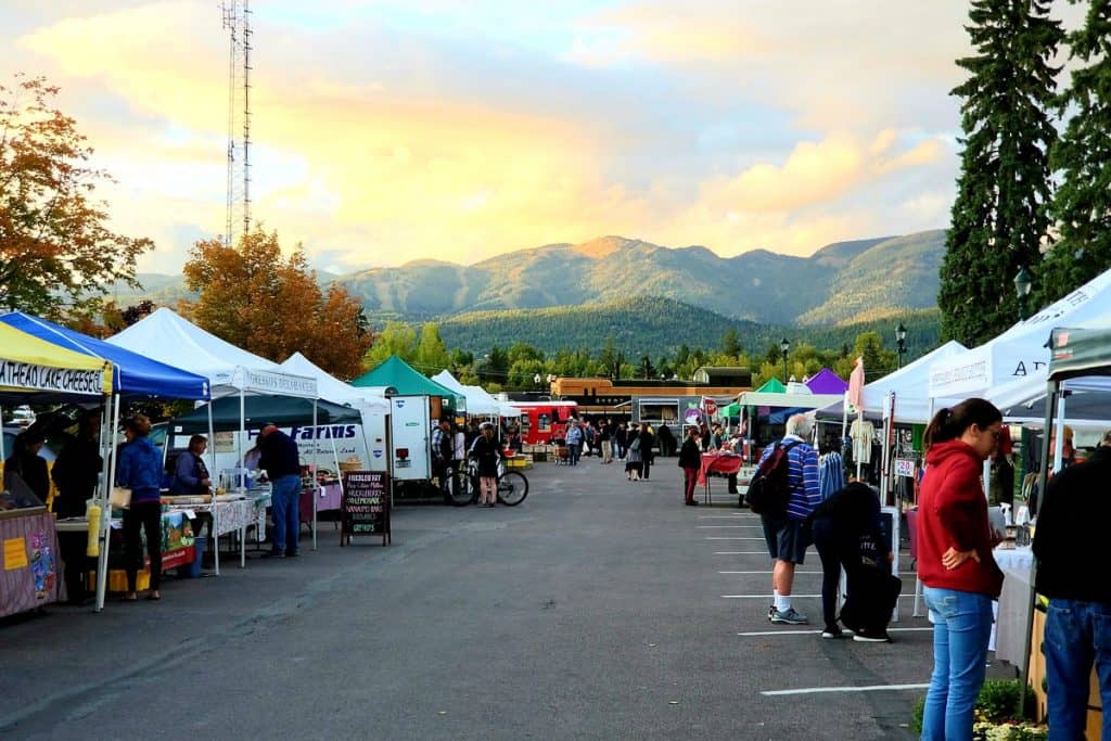 whitefish Montana Farmers market view of the market stands with people and a train engine and big mountain in the background