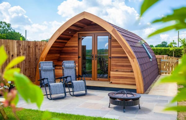 Swallows Field Adult Glamping Pods Essex view of the front of the pod with doors, chairs and a firepit