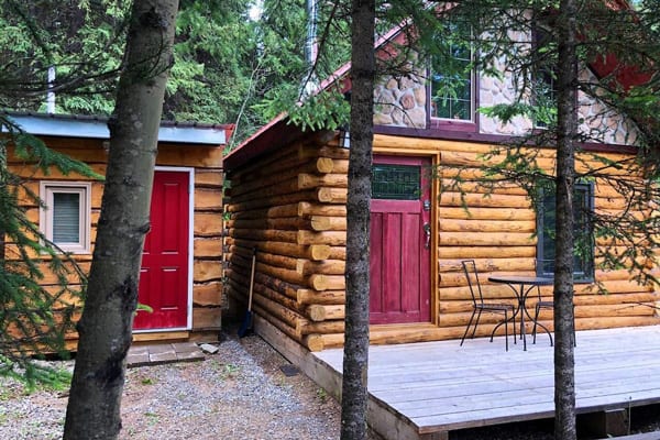 Bear Bungalow Glamping in Alberta Canada view of the cabin with deck, red door and trees