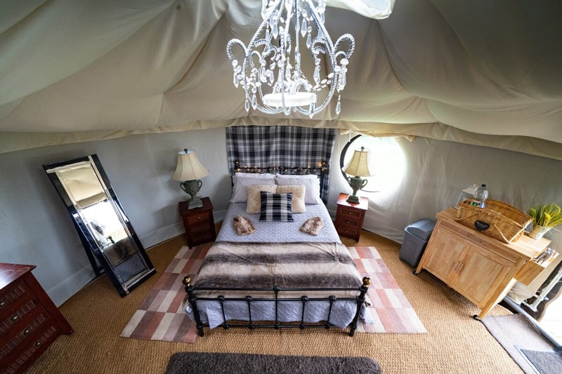 Bedw Snowdonia Glamping Nomadic Yurt view of the inside with bed, chandelier and mirror and dresser
