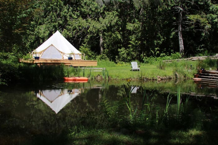 Glamping by the Pond view of a pond with the bell tent in the background next to pond and a chair on grass