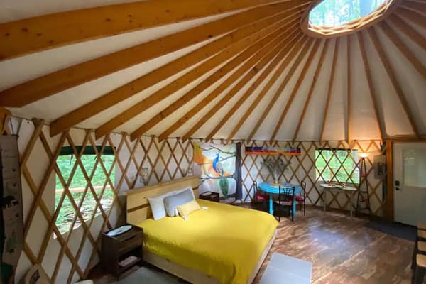 Creekside Yurt Asheville NC view of the inside with bed, table and interior lattice woodwork