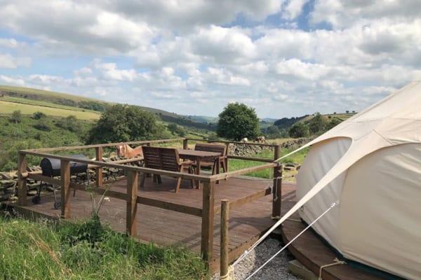 Glamping bell tent view of the tent and deck with the green valley in the background