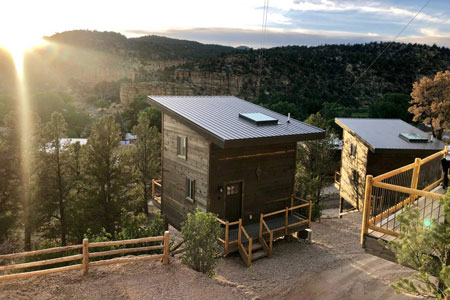 view of two east zion glamping treehouses at sunset on a hill side
