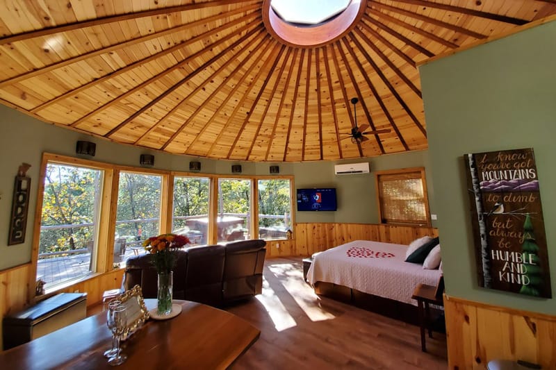 view of inside of Eureka yurts in Arkansas with bed, couch and table