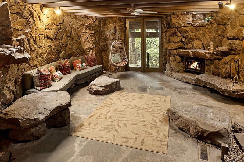 view of basement of glamping cottage Arkansas with stone walls and furniture, couch and fireplace