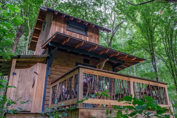 Peaceful Forest Treehouse Asheville NC view of the front of two story treehouse with deck among the trees