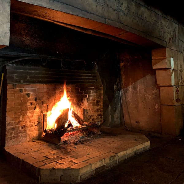 large brick fireplace with fire going