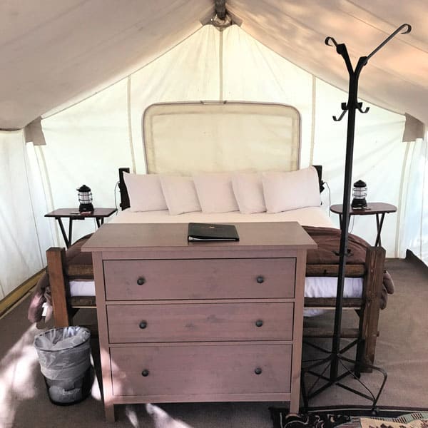 Inside standard tent Under Canvas Glamping Glacier National Park with view of bed, coat rack and dresser