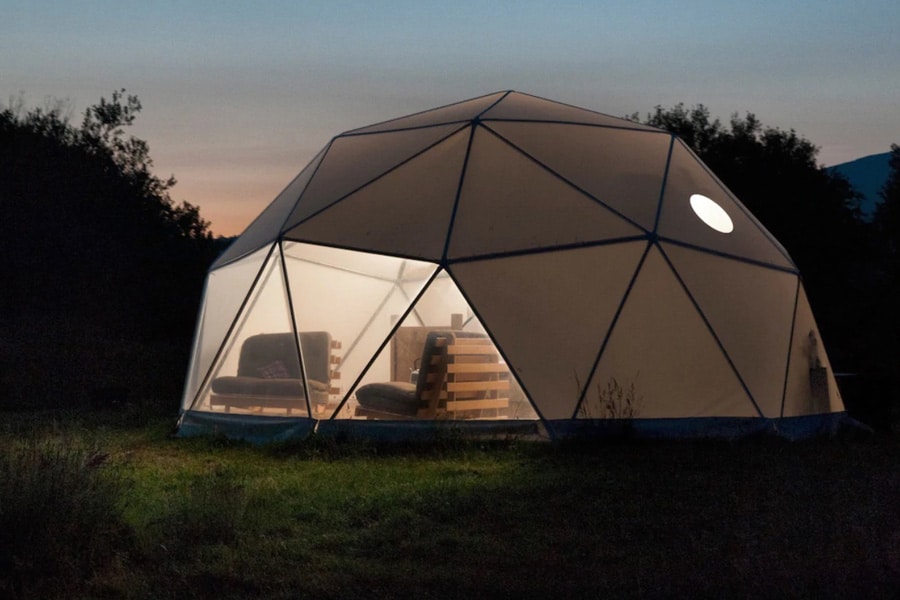 Dome Glamping North Wales view of geodesic dome at night with couches seen in the window