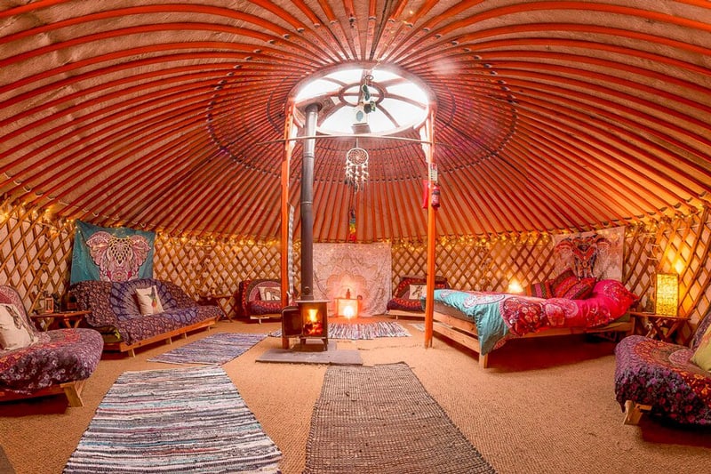 Luxurious Yurts North Wales in Stunning Mountain Location view of inside the yurt with bed, couch, chairs rugs and sky dome, lots of colors