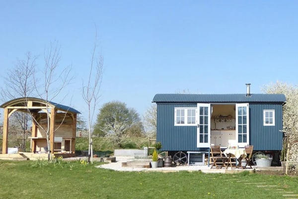 blue glamping hut peak district with door open and tables in front and covered deck nearby