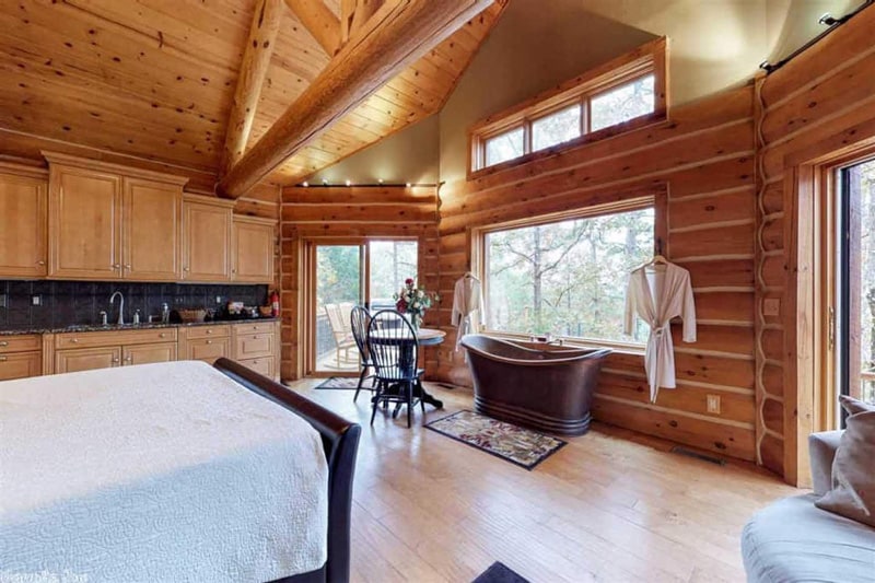 inside view of log cabin Arkansas with bed, tub, kitchen and windows