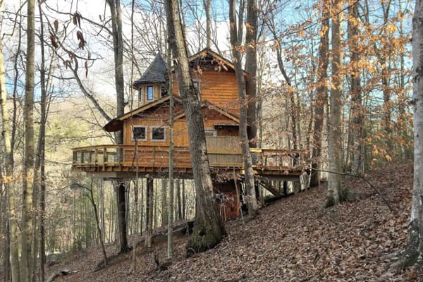 Asheville Glamping Treehouse of Luxury view from the side with wrap around deck on a hill