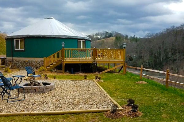 top luxury yurts in North Carolina view of the green yurt next to the river with a firepit and wooden deck