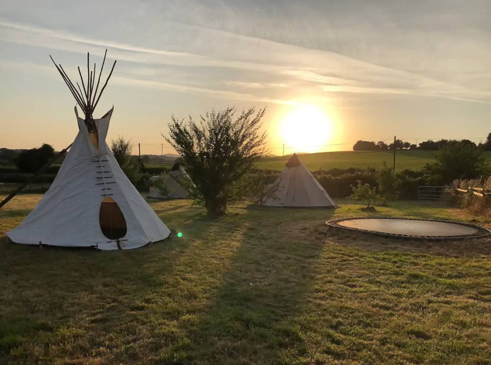 glamping tipis with sunset in the backgorund