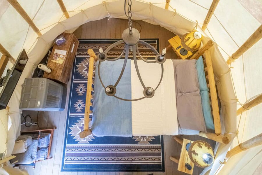 view of inside of tipi from above with bed, tv, furniture and lights