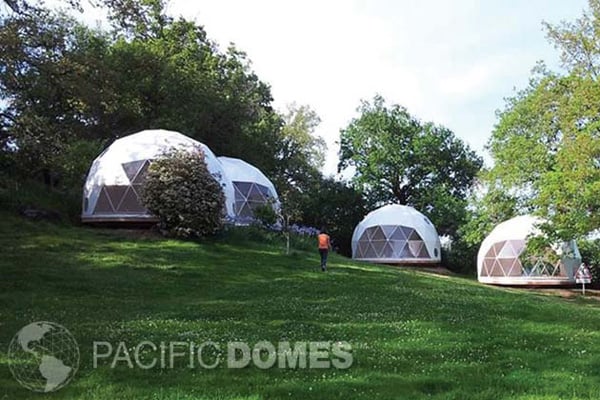 pacific domes glamping domes view of the domes on a grassy hill with 1 person