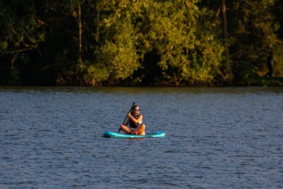 person sitting on paddleboard with oar on the water