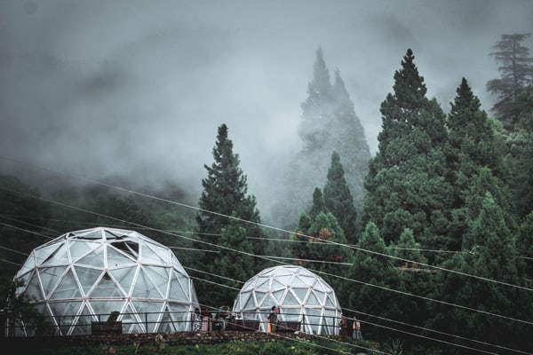 white glamping dome pods  in mountains with trees and fog