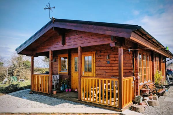 Ed's Railway Sleeper for glamping in Kerry, view of the front of the cabin with deck and chairs