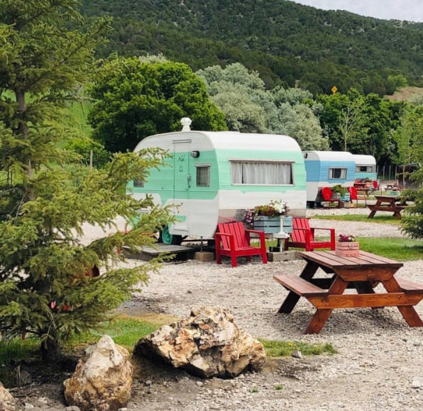 retro trailer glamping view of 3 vintage trailers all different colors with chairs and picnic tables