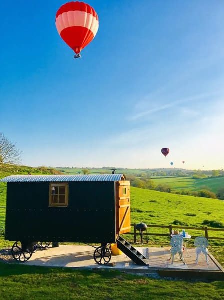 Shephards hut in the Cotswolds view with ot air balloons in the sky