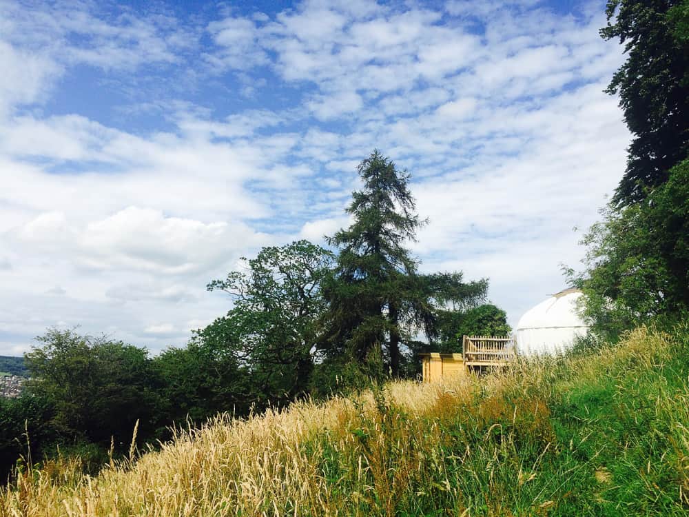 glamping yurt on a hill with trees and sky and clouds