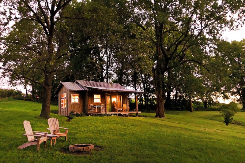 Glamping Cabin at Honey Creek view of cabin with green grass, trees and firepit