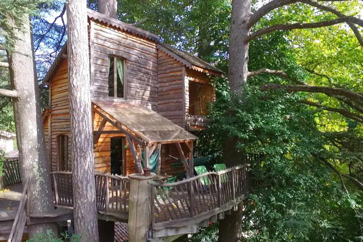 Au Fil de Soi Treehouse with a view from the outside of the glamping treehouse with trees around the wooden structure
