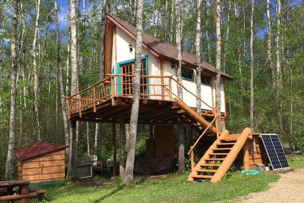 Hidden Treehouse Glamping Alberta Chalet view from the outside with stairs leading up to the deck and treehouse