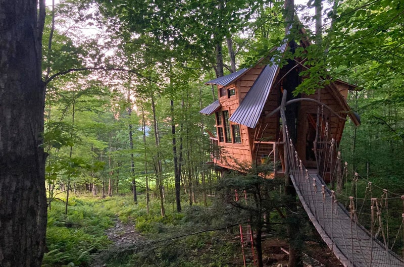 Vermont Glamping Treehouse at Bliss Ridge Farm view from wooden bridge to the front with the quirky treehouse and tree around