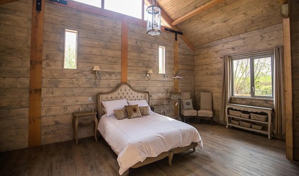 Glamping cabin inside view wit bed and high ceiling and window
