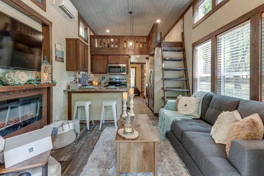 Serenity by The Falls tiny home view of the inside with couch, kitchen, fireplace and loft