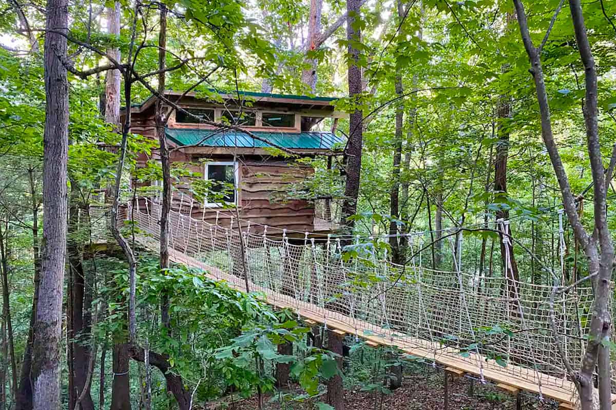 Asheville Treehouses in North Carolina featured image view of treehouse with hanging bridge to front door in the woods