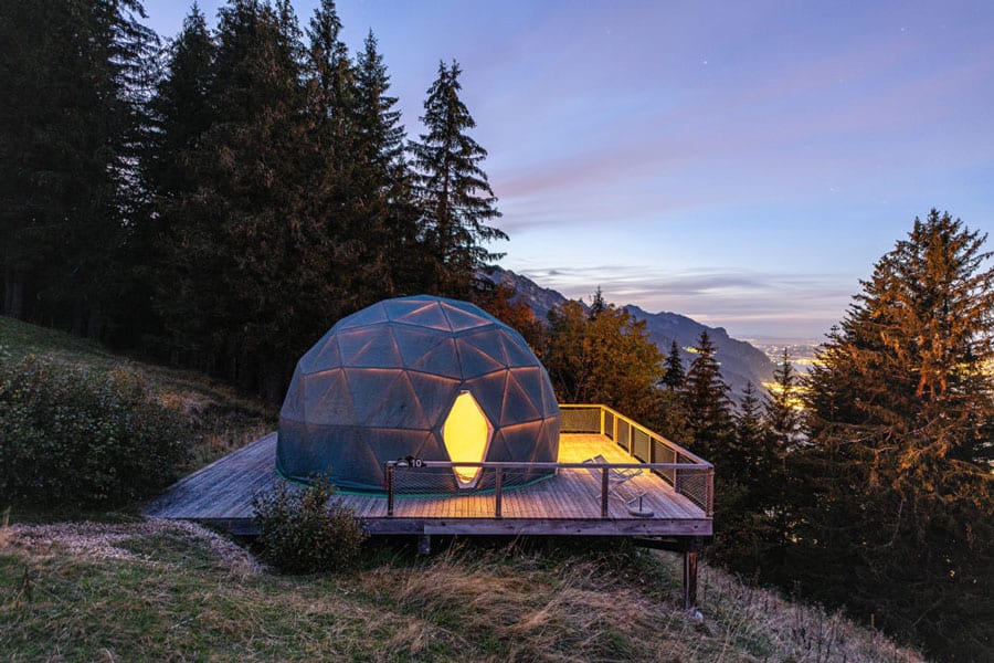 WhitePod Glamping Domes view at sunset with mountains and trees and geodesic dome with deck