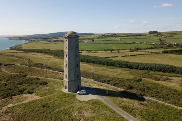 Wicklow Lighthouse Glamping Ireland with a view of the lighthouse in the middle of the countryside and the sea to the left